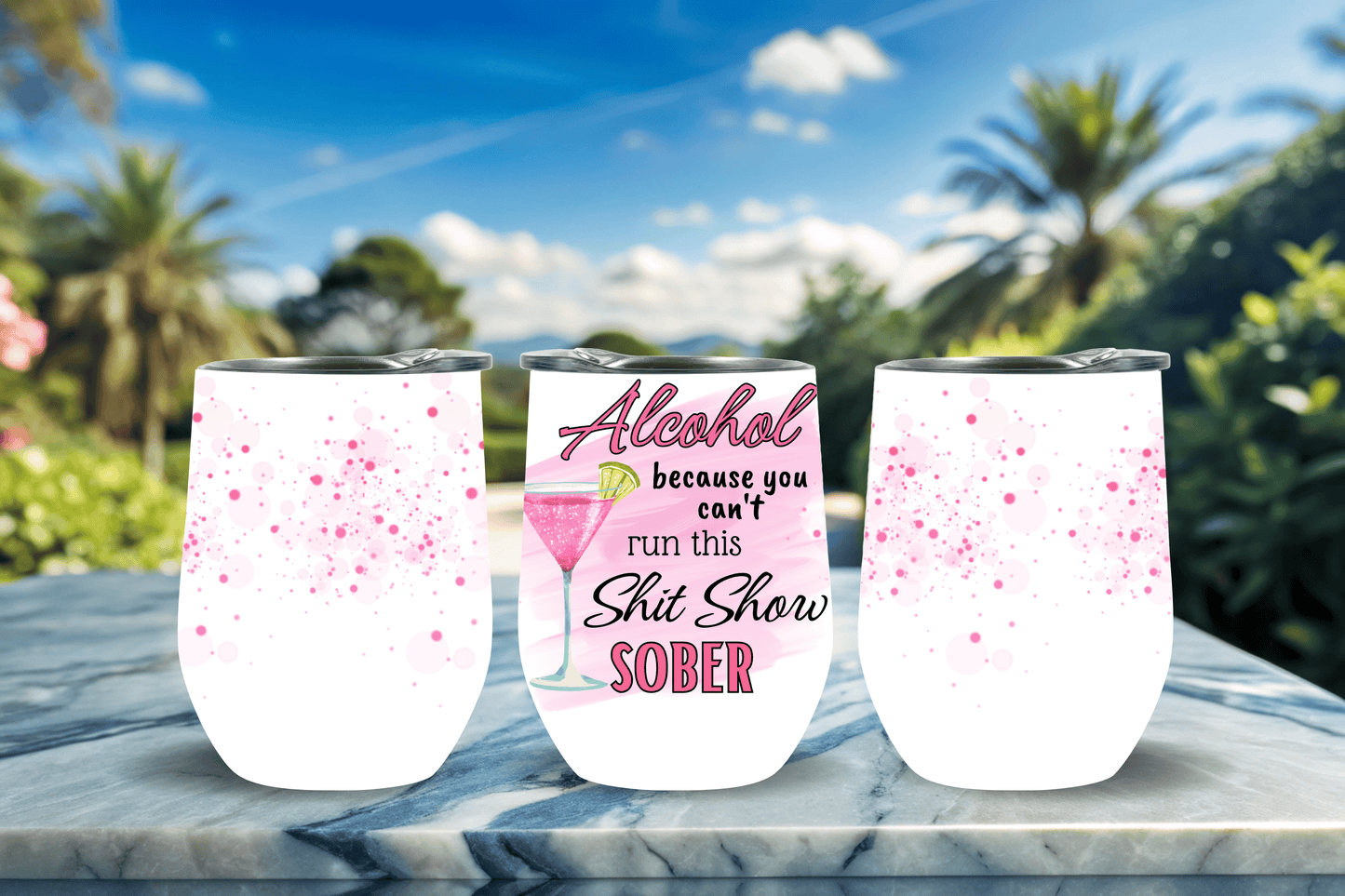 Funny 12oz stemless wine tumbler with pink watercolour splatter design and bold 'Alcohol – because you can't run this shit show sober' slogan, shown in three angles on a marble surface